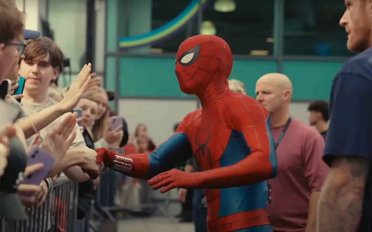 Spider-Man in the red-and-blue suit shaking hands with a crowd along a barrier